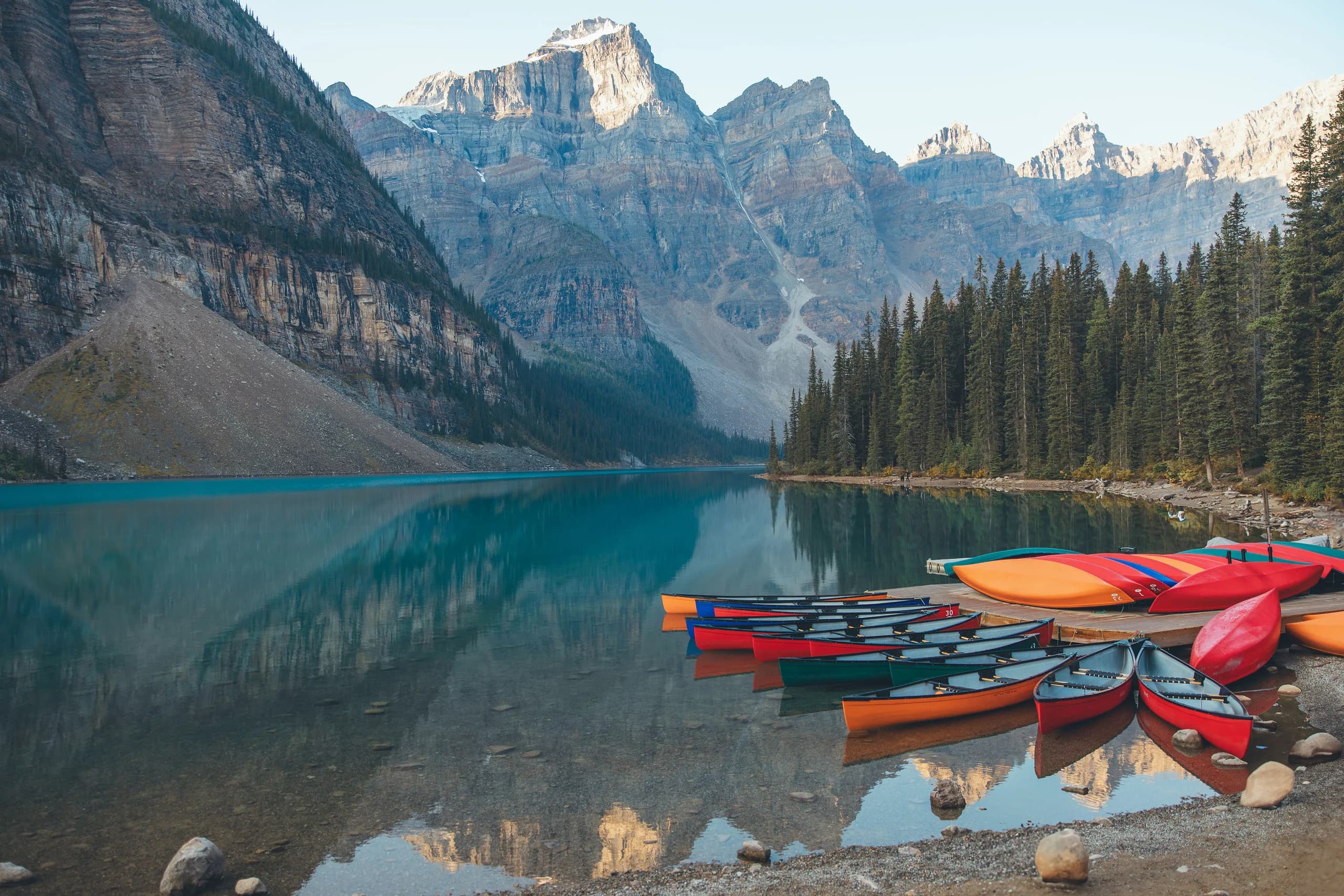 Colourful canoes beside the turquoise water of Moraine Lake