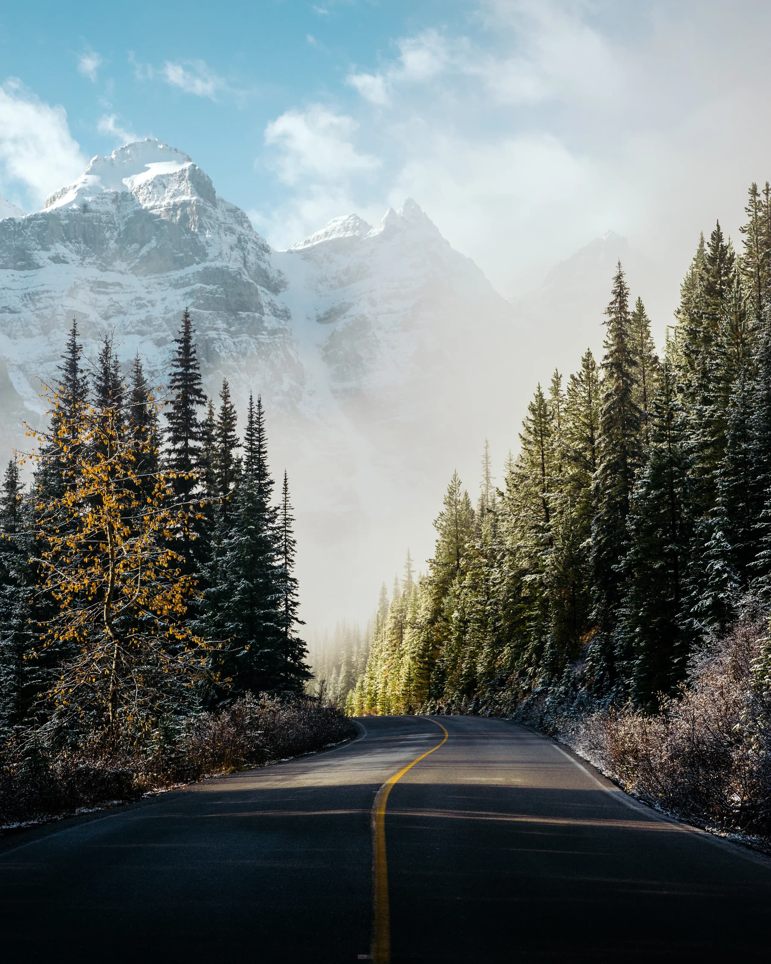 Une route de montagne tranquille menant vers des sommets enneigés près du lac Moraine en hiver